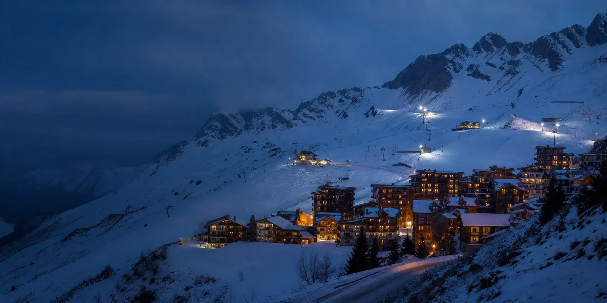 A high Alpine ski village and lit slopes at blue hour