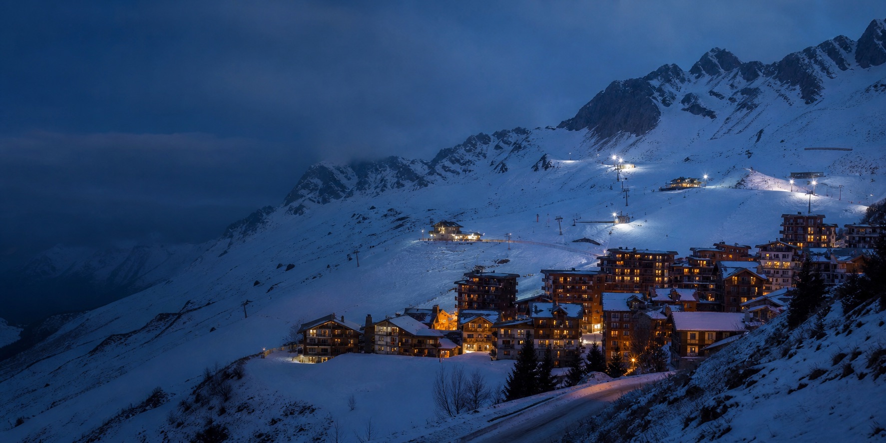 A high Alpine ski village and lit slopes at blue hour
